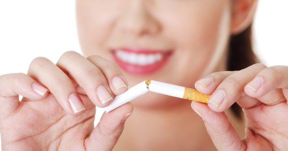 A woman breaking a cigarette in half to represent giving up smoking