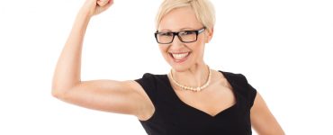 Woman wearing black dress with arm raised in triumph at her weight loss