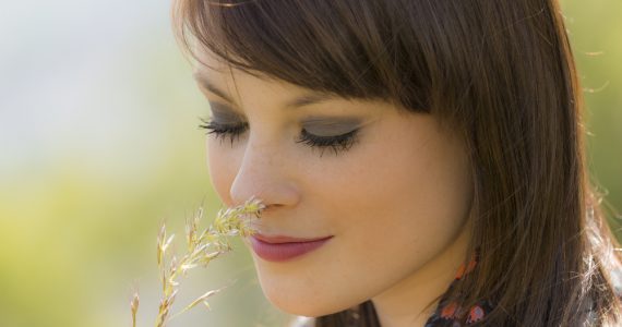 Close up of woman smelling wild flowers to show hay fever