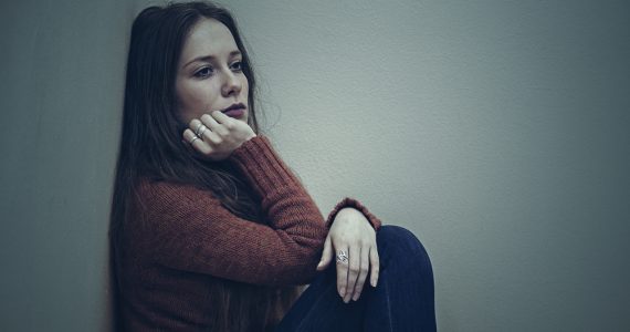 Woman sitting on floor looking sad to represent mental health