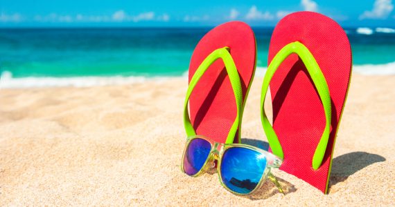 Flip flops and sun glasses in the sand on a sunny beach