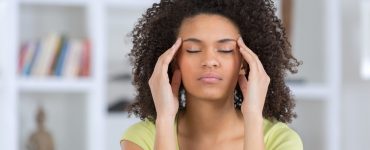 Woman holding hands to the side of her head to represent a headache