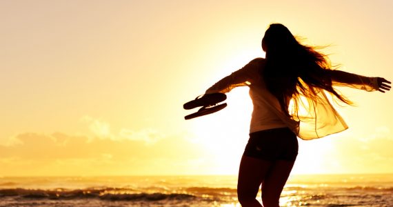 Woman dacning on beach at sunset on holiday